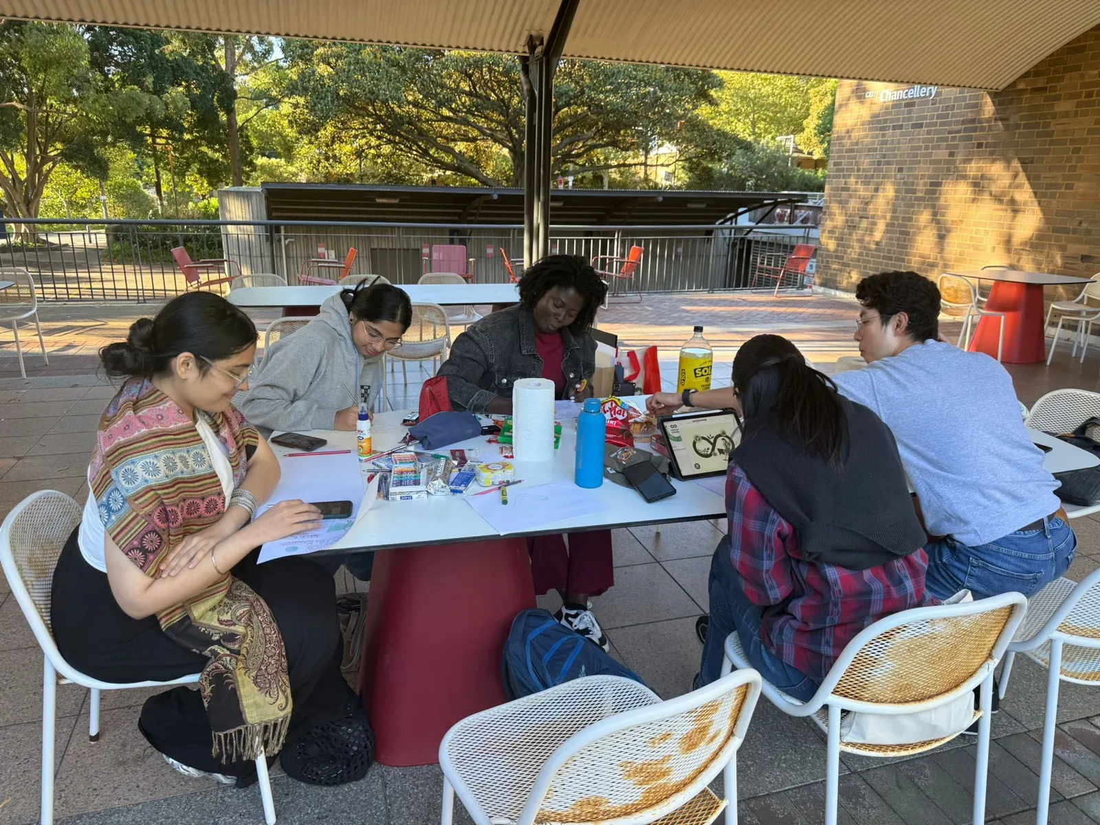 Students around a table sketching recycling signs and reviewing materials